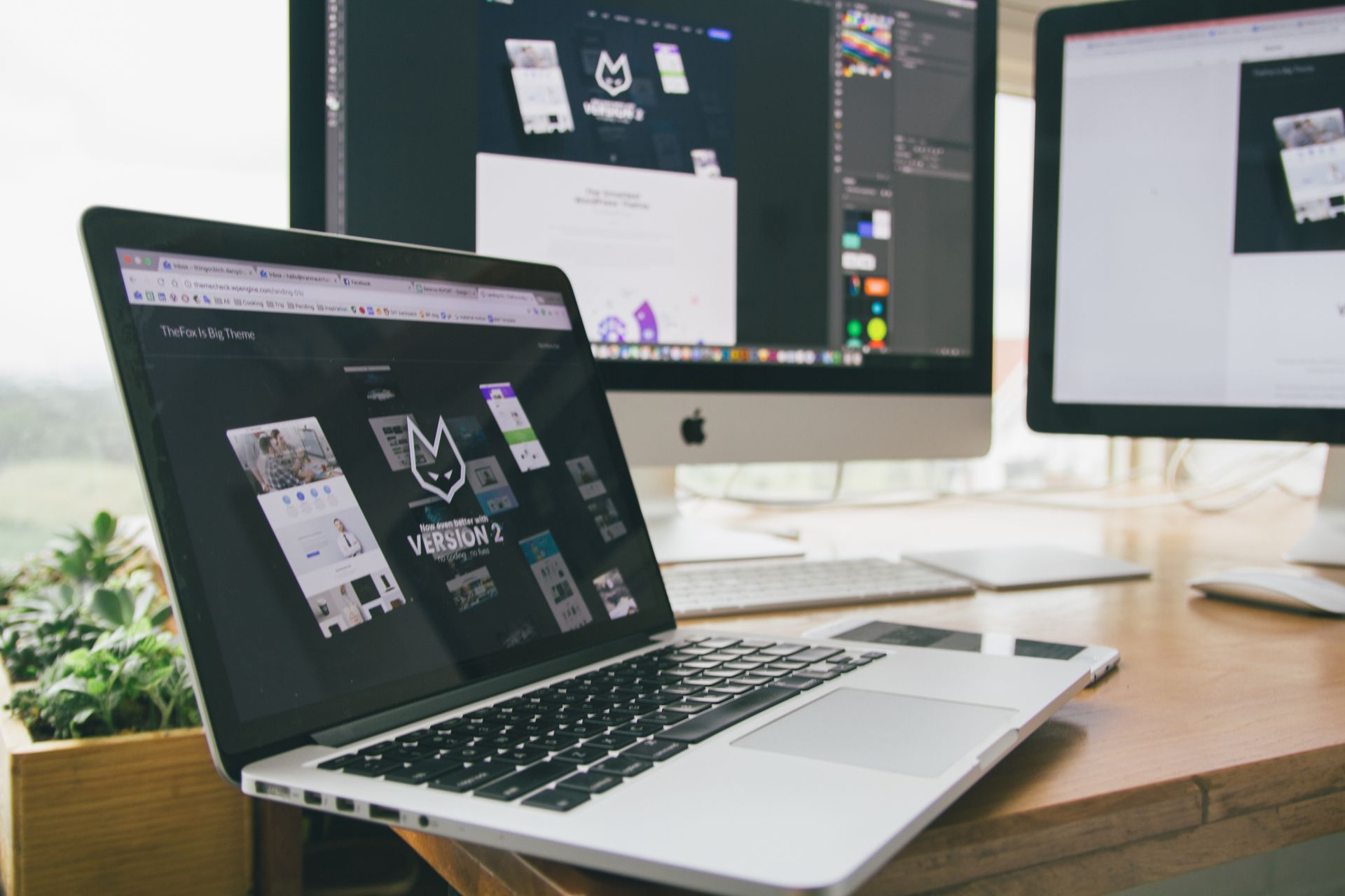 Laptop and monitors showing custom web app design work