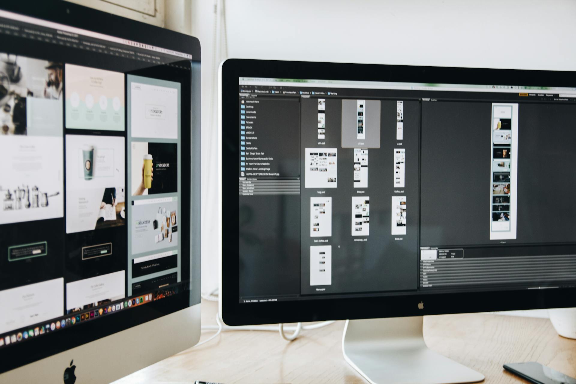Designer's monitors showing website mockups and layouts